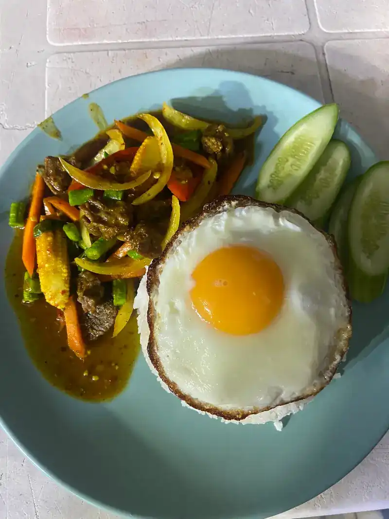 A rice plate: stir-fry with baby corn, carrot and peppers, a fried egg and cucumber