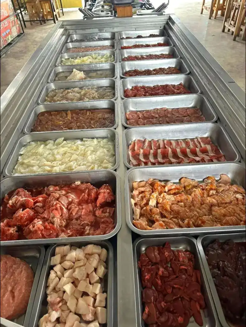 The buffet counter: rows of steel trays with raw meat