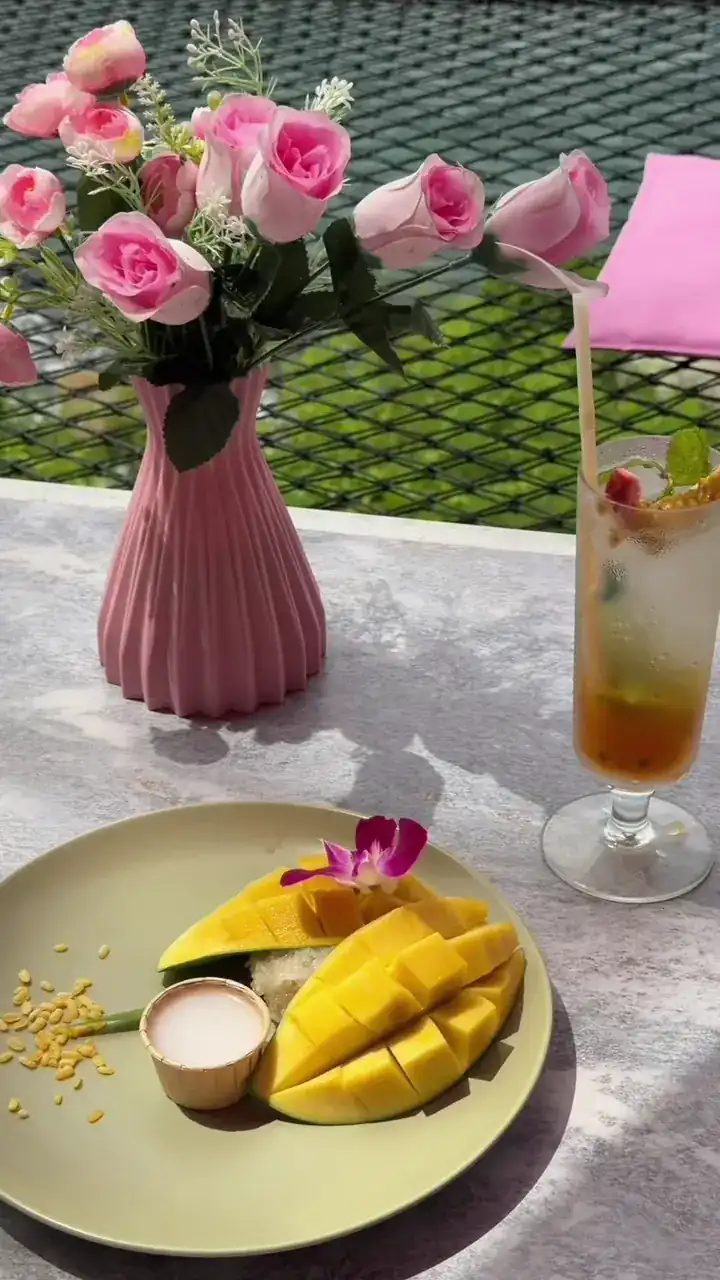 Mango sticky rice beside a vase of pink flowers / ข้าวเหนียวมะม่วงข้างแจกันดอกไม้สีชมพู