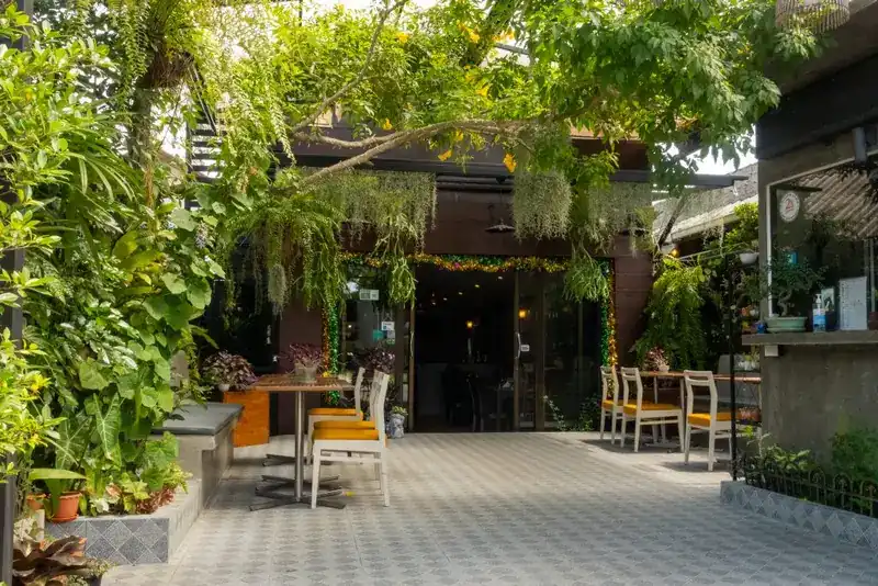 The entrance to the restaurant seen through the garden, under hanging plants