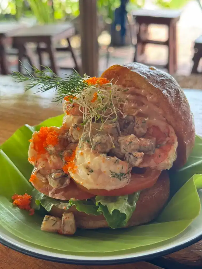 A burger topped with prawns on a banana leaf