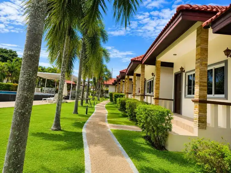 A garden path between palm trees and the bungalows