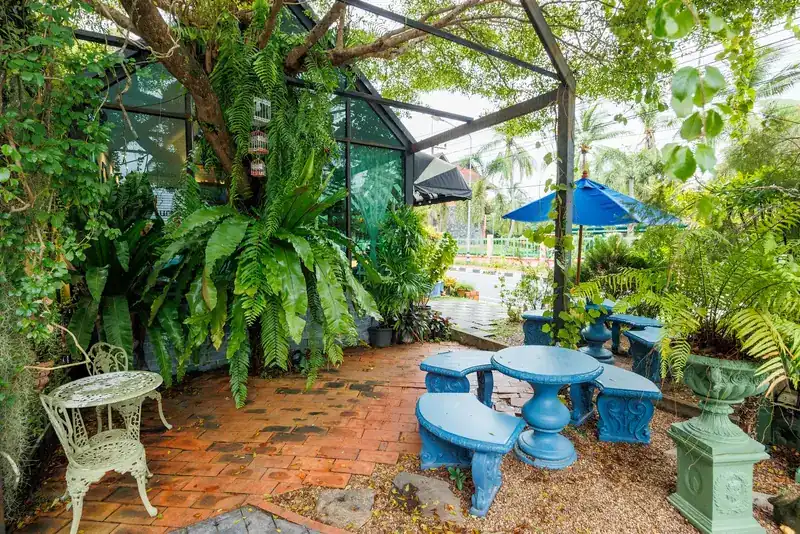 Blue garden tables and stools among ferns under a tree