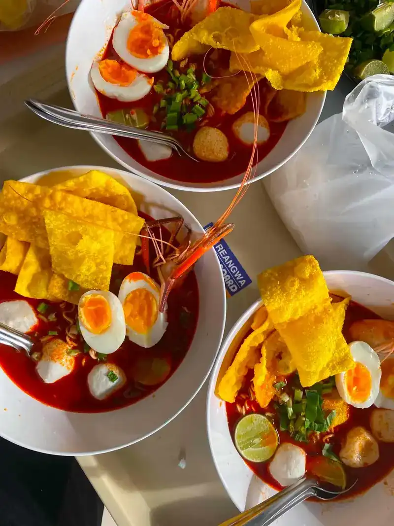 Three bowls of tom yum river prawn noodles on a table, seen from above