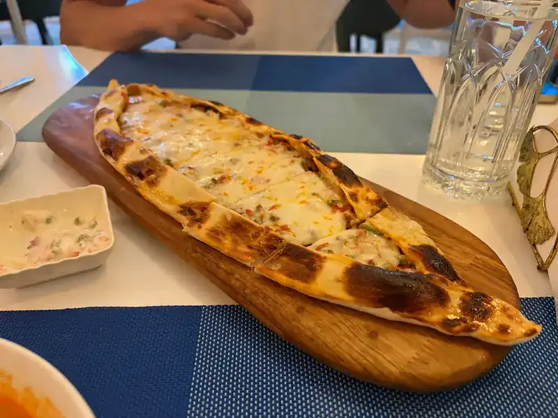 A boat-shaped cheese pide on a wooden board