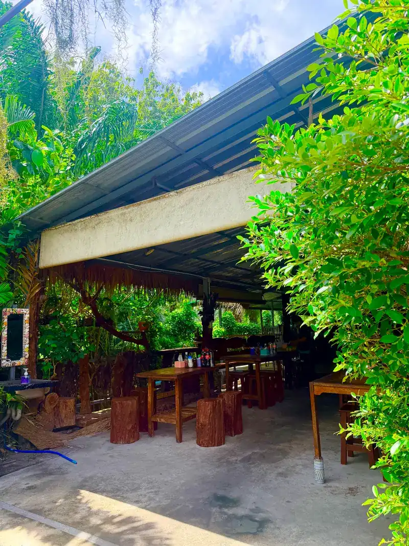Open-air seating under a roof, framed by trees