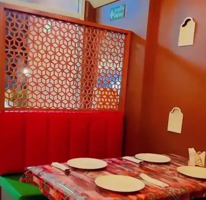 A red booth under a carved orange screen, the table laid with plates on a patterned cloth