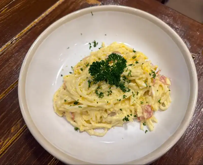 Spaghetti in a creamy sauce topped with parsley, in a white bowl