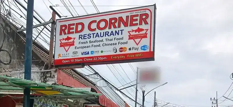The Red Corner Restaurant sign above Taina Road, red letters on white