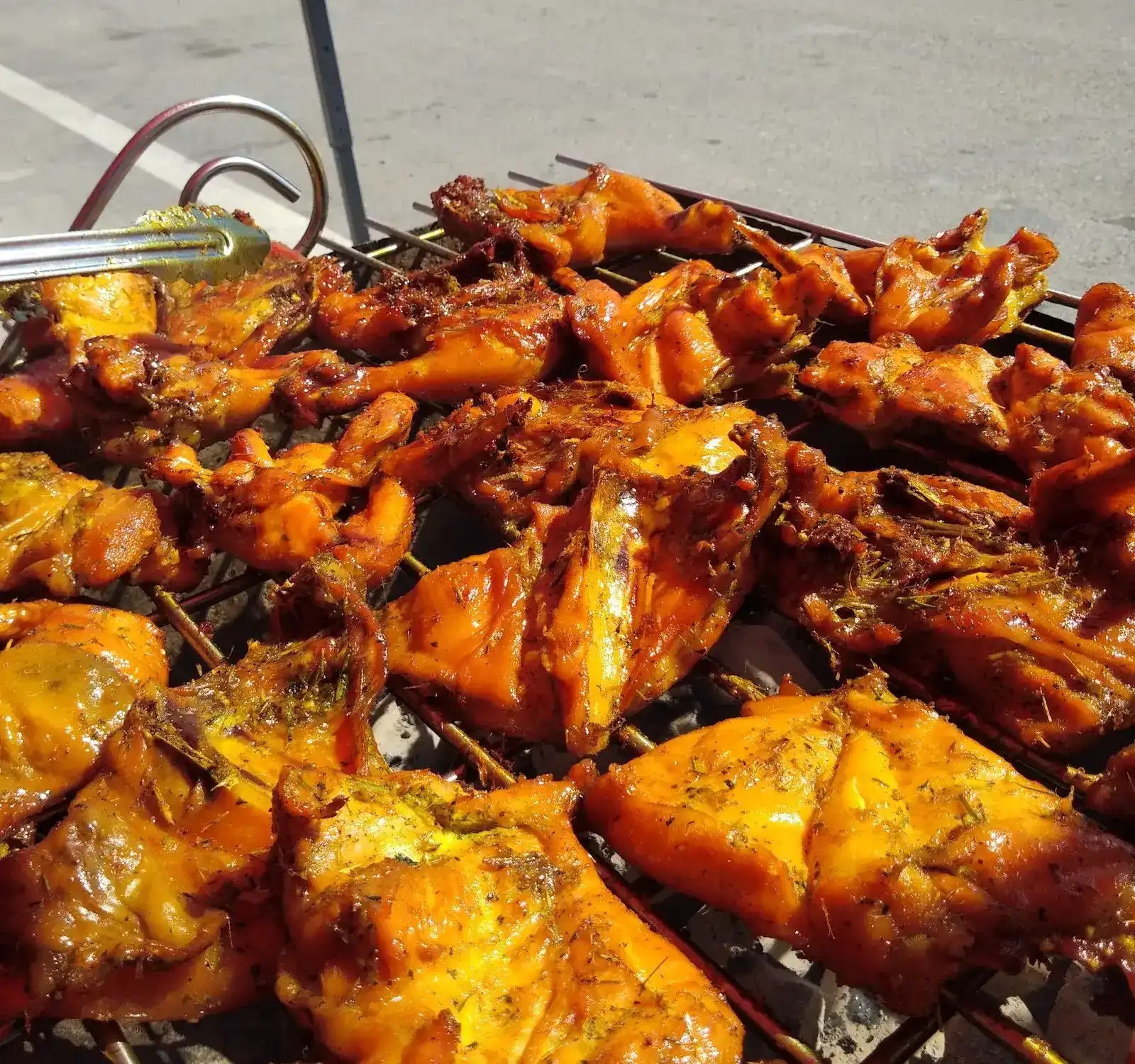 Herb-marinated chicken pieces on the charcoal grill beside the road