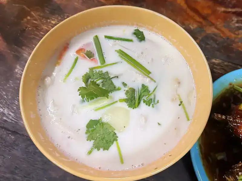 A bowl of coconut milk soup with coriander and spring onion