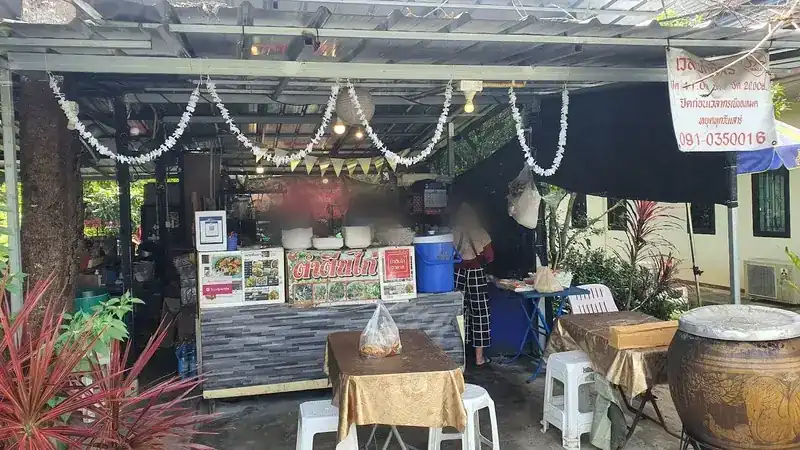 The kitchen counter under the tin roof, with white garlands, the shop sign and cloth-covered tables