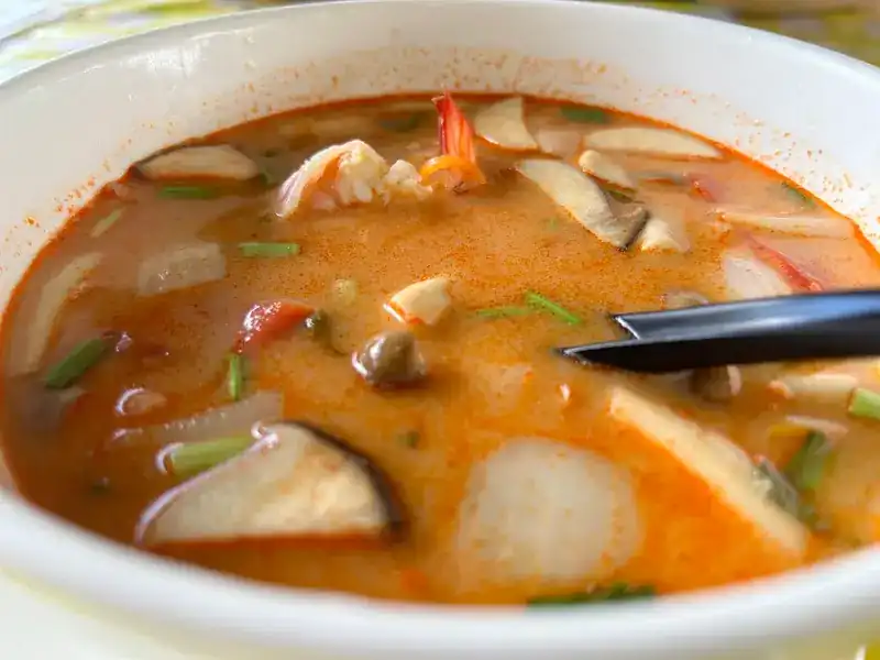 A bowl of tom yum with prawn, mushrooms and herbs