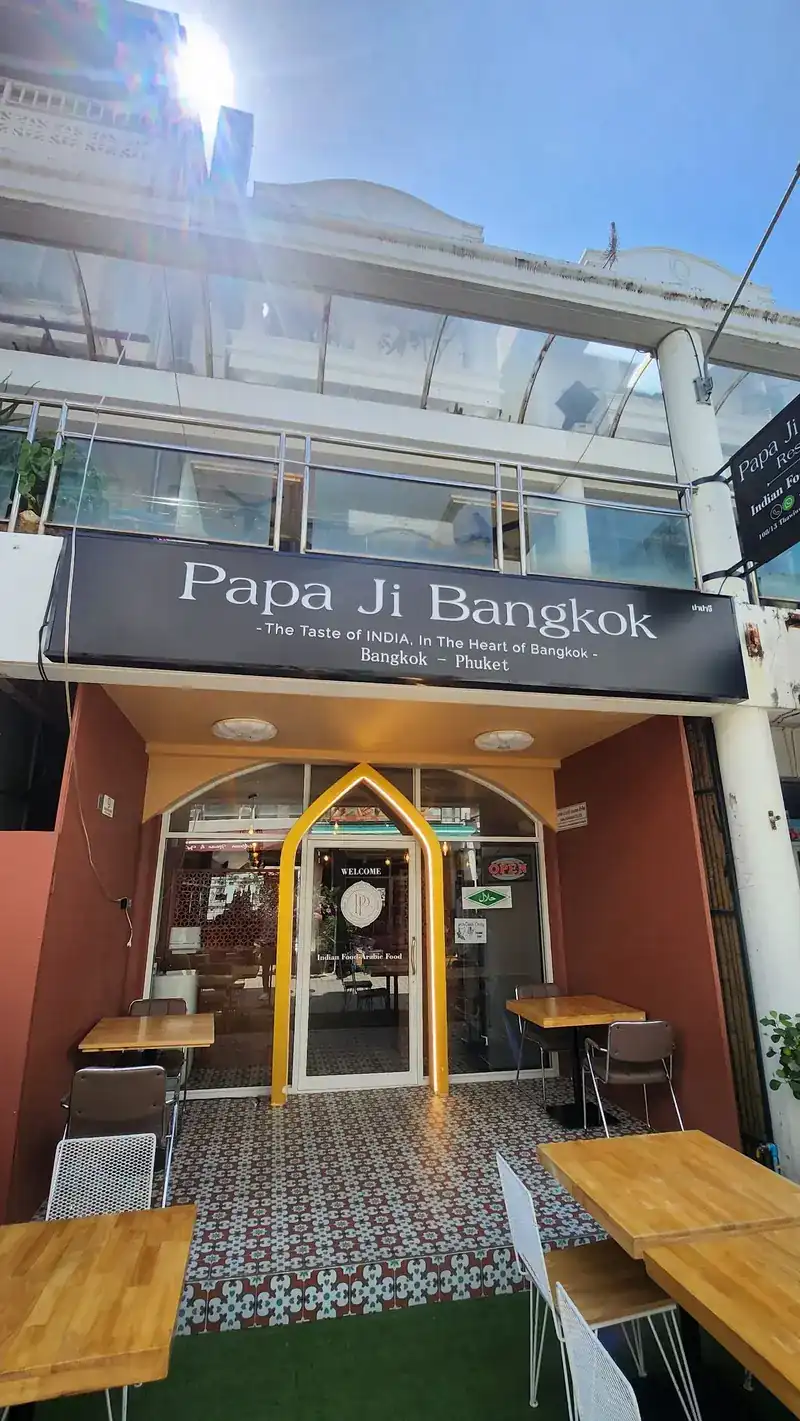 The front of Papa Ji Bangkok on Thaweewong Road: a black sign over a gold doorway, with tables outside
