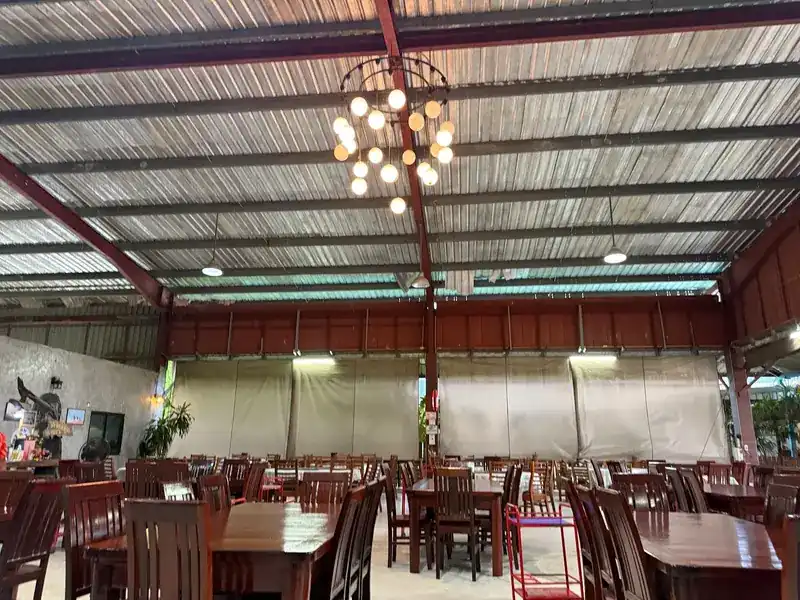 The large dining hall with rows of dark wooden tables and chairs under a high steel roof
