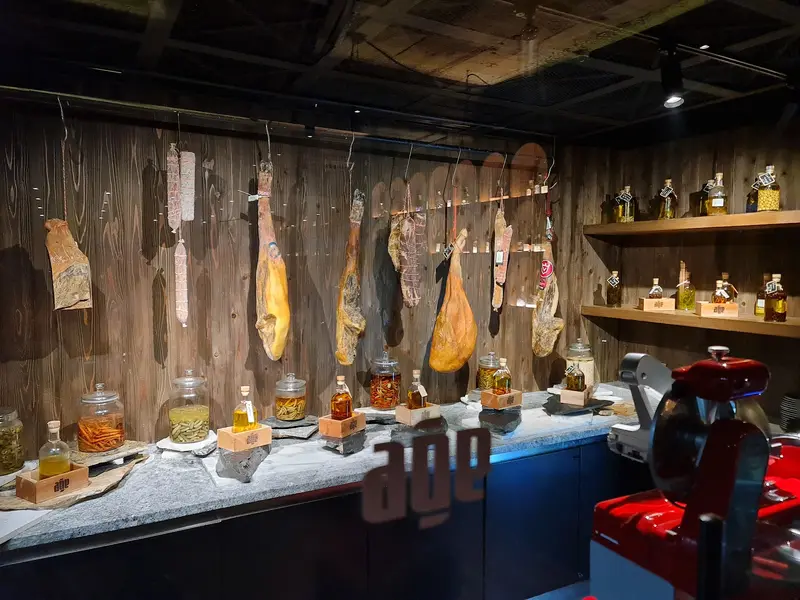 Hams hanging over the charcuterie counter, jars on a stone ledge / แฮมแขวนเหนือเคาน์เตอร์ชาร์กูเตอรี และโหลแก้วบนชั้นหิน