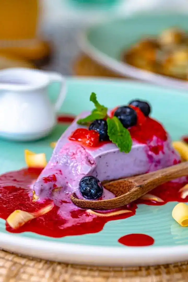 A slice of berry cake with blueberries and mint