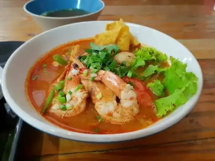 Creamy tom yum noodle soup with prawns, lettuce and a crisp fried wonton