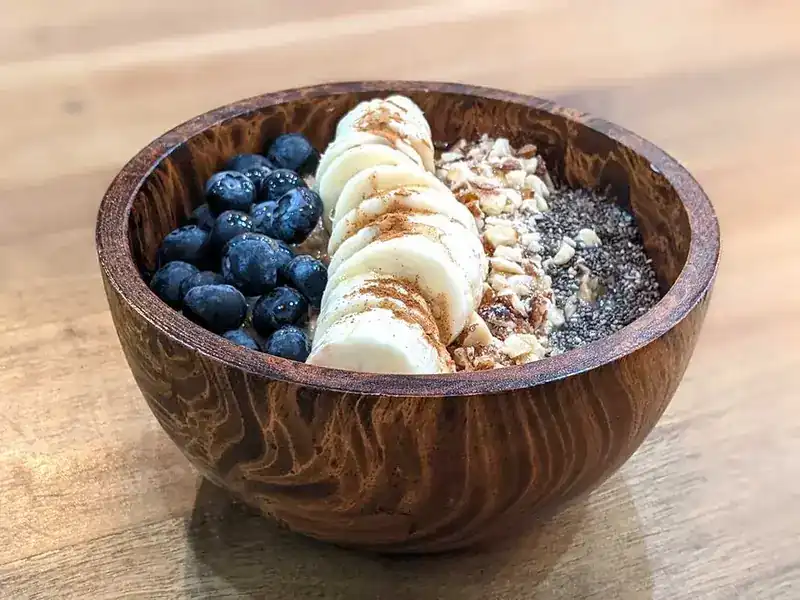 Oatmeal in a wooden bowl with blueberries, banana and chia seeds