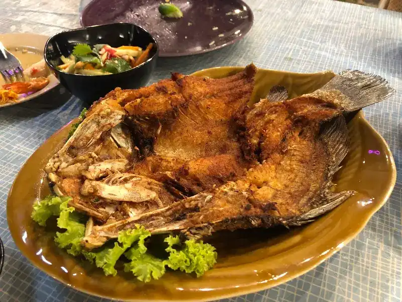 A whole fried fish on lettuce
