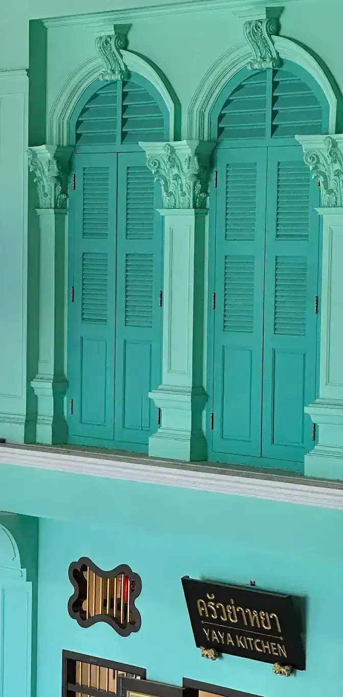 The mint-green shophouse front: tall louvred shutters upstairs and the black sign of ครัวย่าหยา, Yaya Kitchen, below