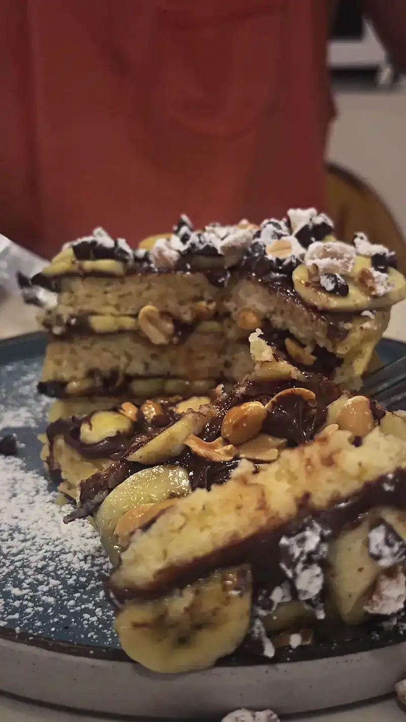 A stack of pancakes with Nutella, banana and peanuts