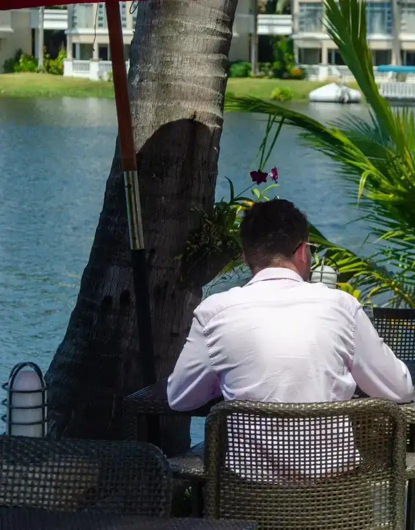 A table on the terrace under a coconut palm, with the lake behind