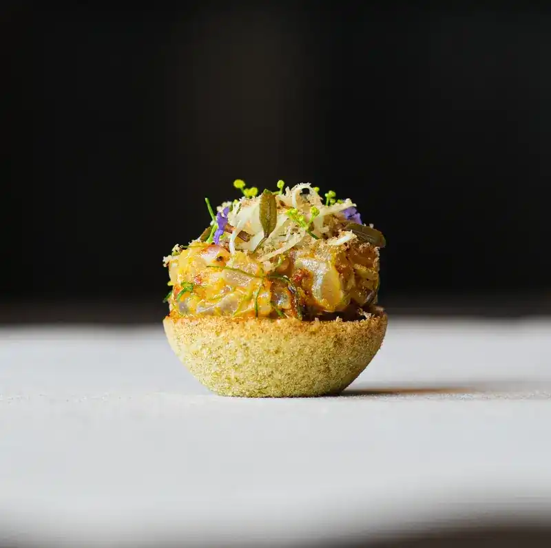 A small tart piled high with herbs and tiny flowers