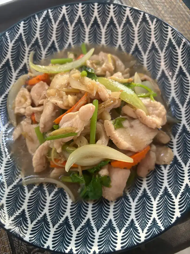 A stir-fry with onion, carrot and spring onion in a patterned bowl
