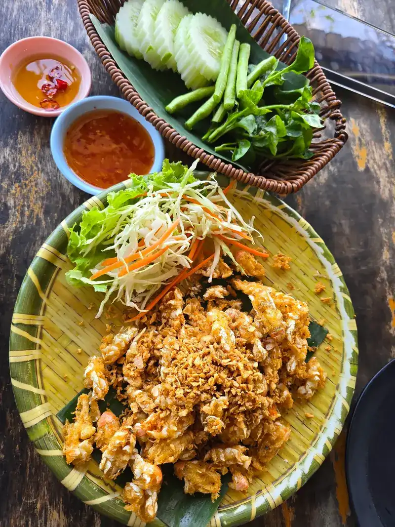 Fried sea cicadas on a woven bamboo plate with cabbage and carrot, fresh vegetables and two dips