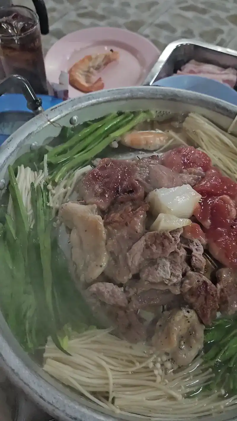 The pan filled with meat, greens and mushrooms