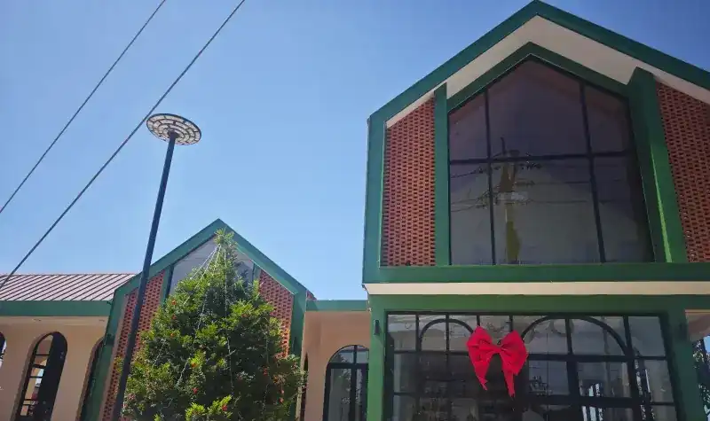 The building from outside: green-framed gables, open brick screens and tall black-framed windows