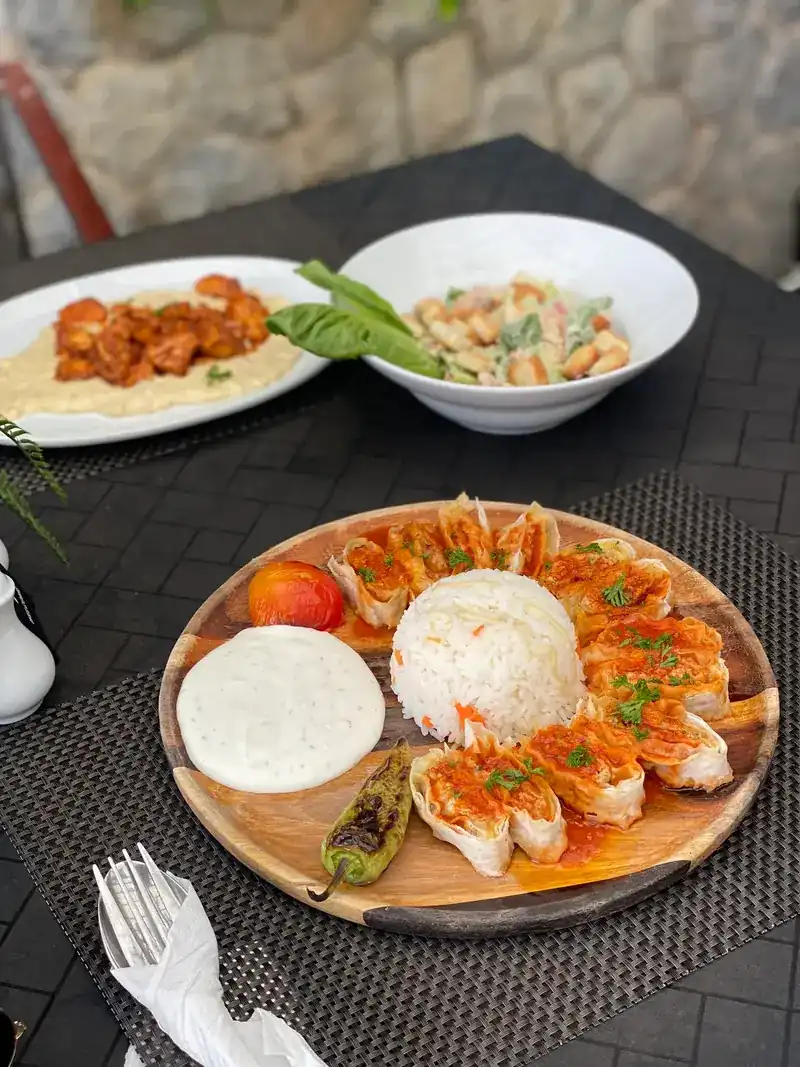 Dishes on the table: a wooden board with rice, bread and a grilled pepper, and more plates behind
