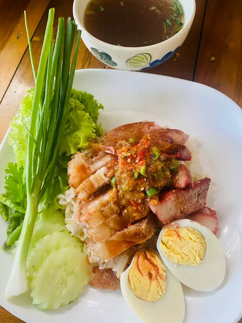 Pork rice with red pork, crispy pork, boiled egg, cucumber and a bowl of soup