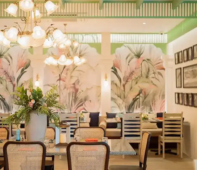 Dining room with palm-leaf murals, rattan chairs and glass chandeliers