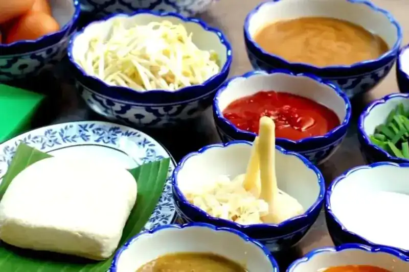 Rows of small blue-and-white porcelain bowls holding sauces, bean sprouts and spring onions