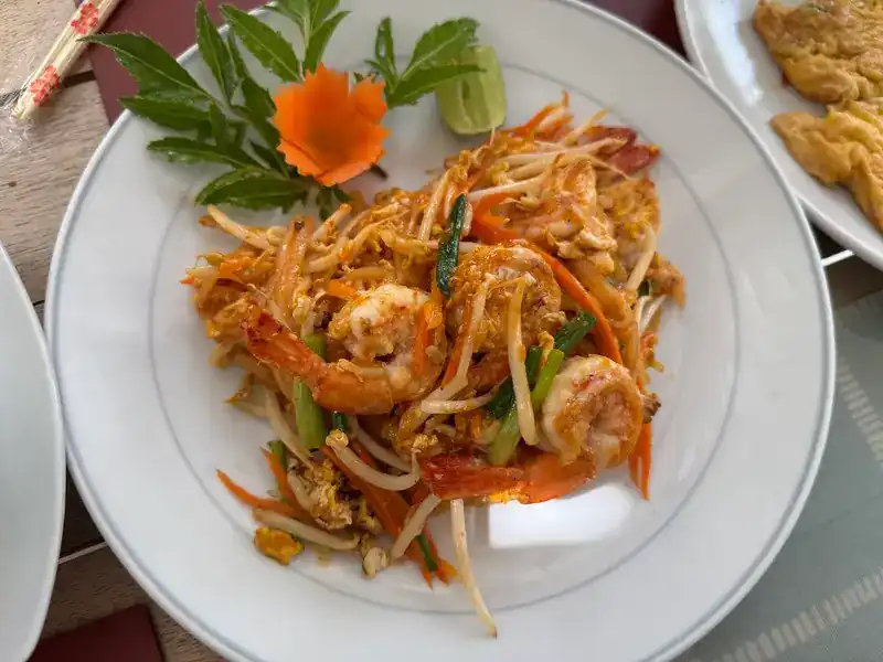 Pad thai with prawns, a carved carrot flower and lime