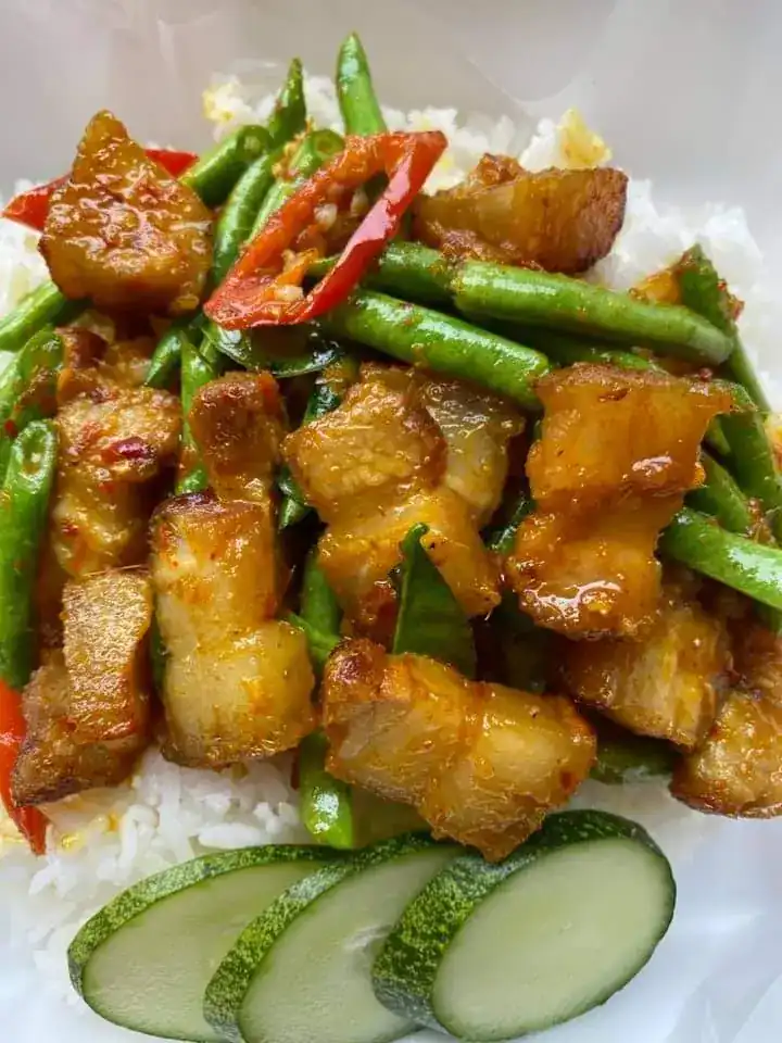 Crispy pork belly stir-fried with long beans and red chilli over rice — หมูกรอบผัดเผ็ดถั่วฝักยาวราดข้าว