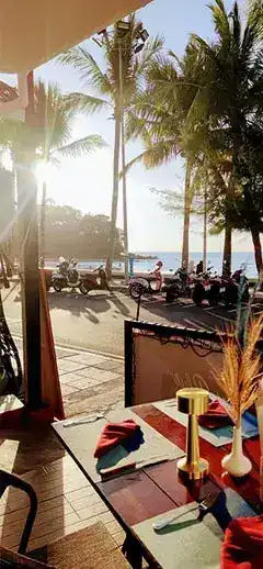 A laid table looking out over Beach Road, palm trees and the sea