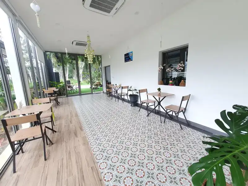 The shop's long room with patterned floor tiles, small wooden tables and glass doors to the garden