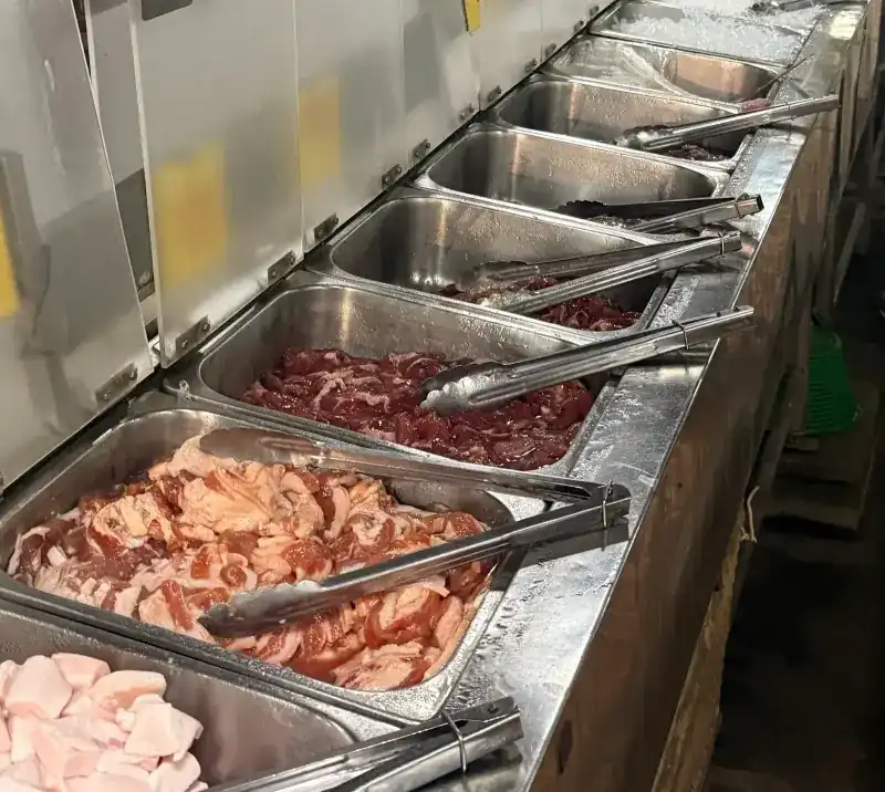 Trays of sliced meat with tongs along the buffet counter