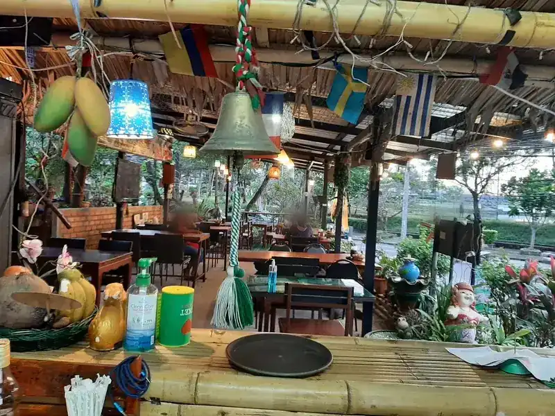 The bamboo bar with a brass bell, flags hanging from the beams and tables looking out to the street | บาร์ไม้ไผ่กับระฆังทองเหลือง ธงแขวนใต้คาน และโต๊ะที่มองออกไปยังถนน