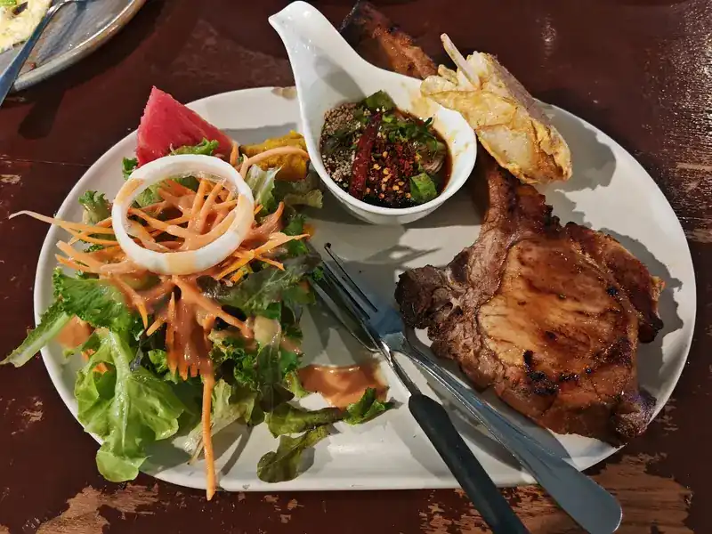 Grilled pork chop with salad, garlic bread and a chilli dipping sauce