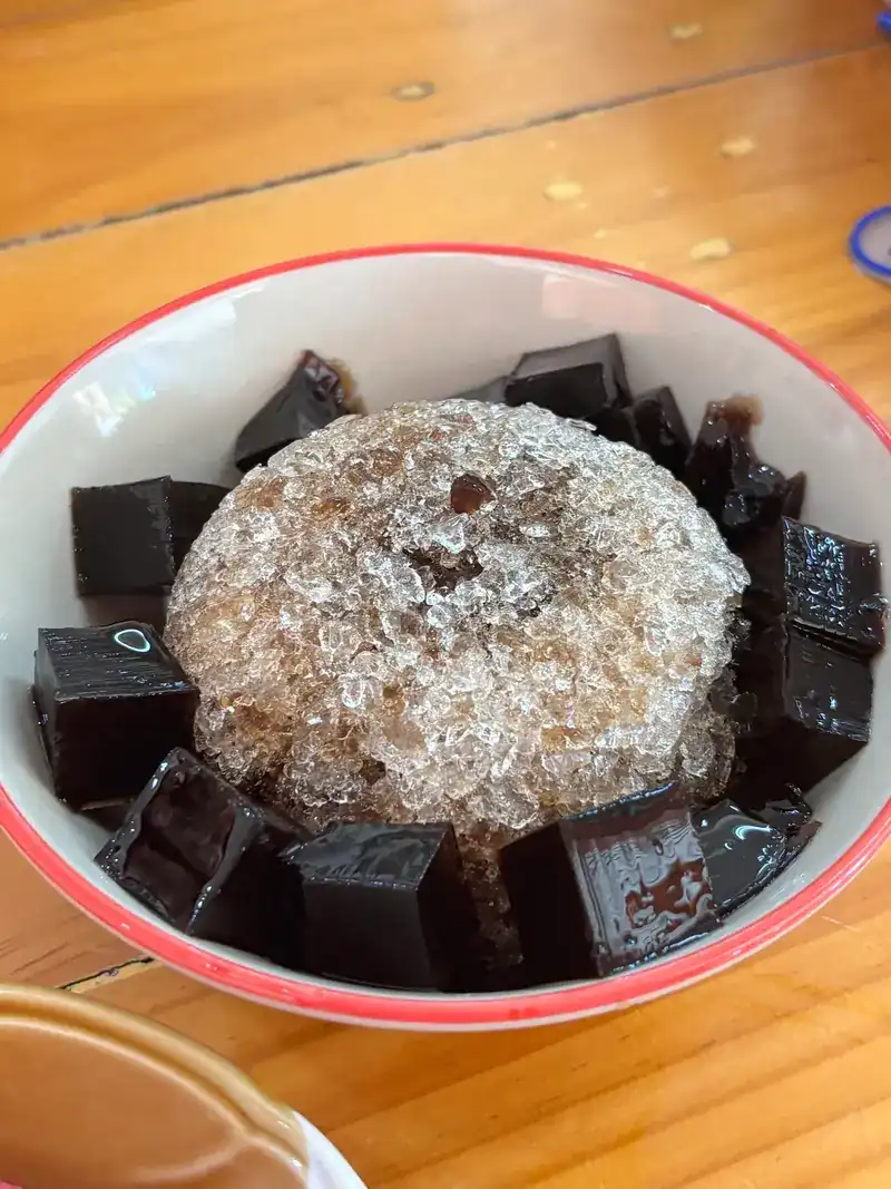 Cubes of grass jelly around a mound of shaved ice in a bowl