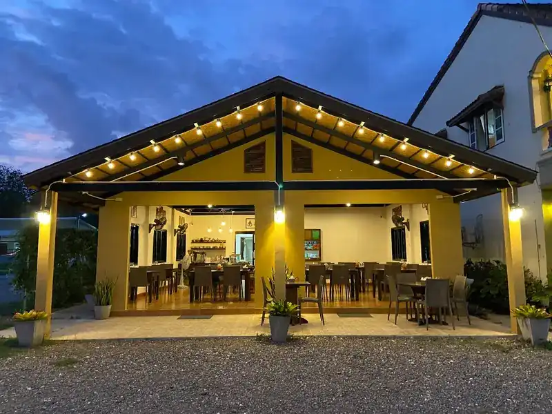 The open-sided yellow dining pavilion at dusk, with lights along the roof