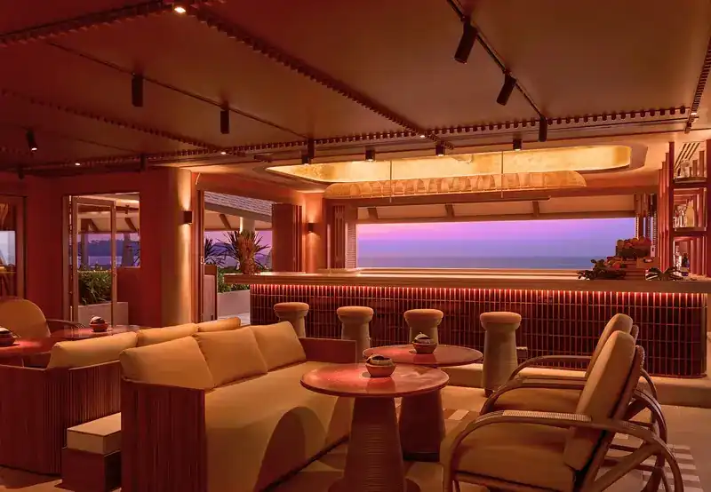 The lounge and bar at dusk, the sea violet beyond the open window