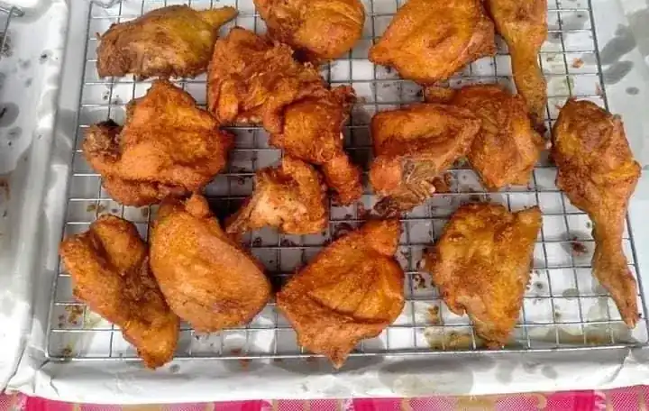Pieces of golden fried chicken resting on a wire rack over white paper