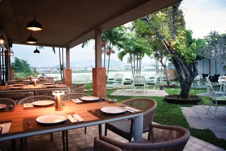 Set wooden tables on the covered terrace, looking out over the garden to the lake