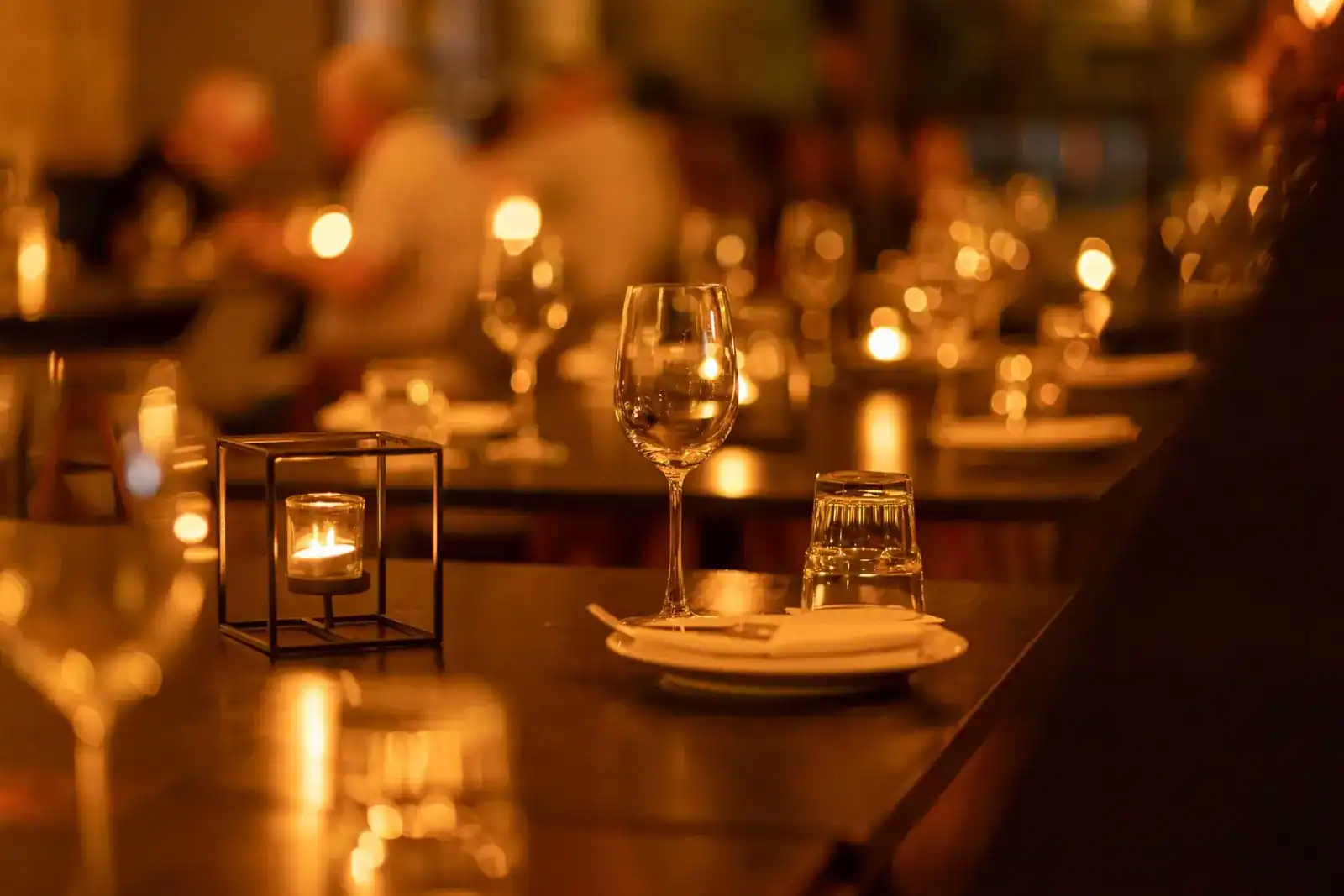A laid table with a tea light and glasses in the evening glow of the dining room