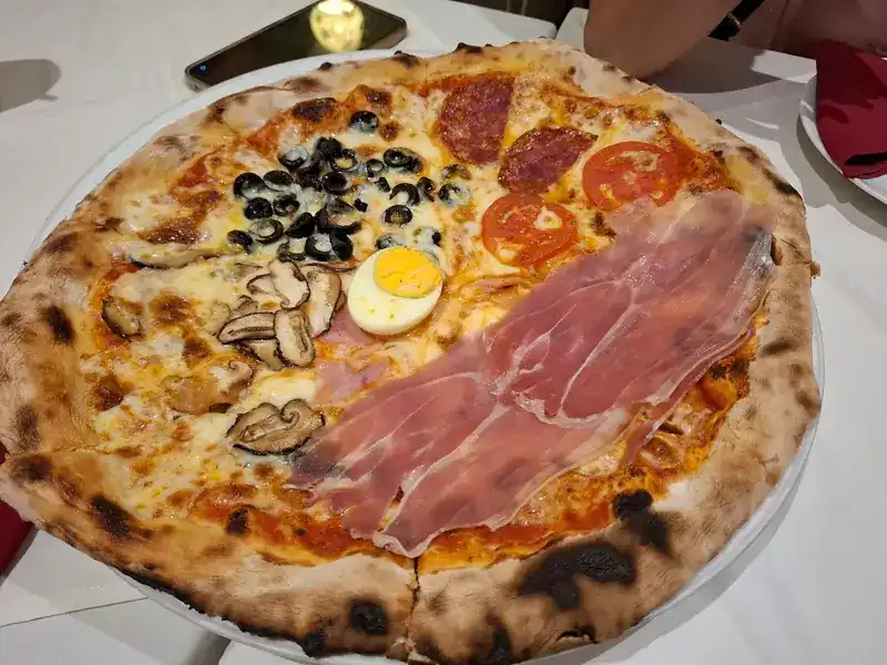 Wood-fired pizza with prosciutto, mushrooms, egg, olives, salami and tomato
